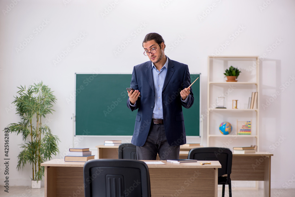 Young male teacher in front of green board