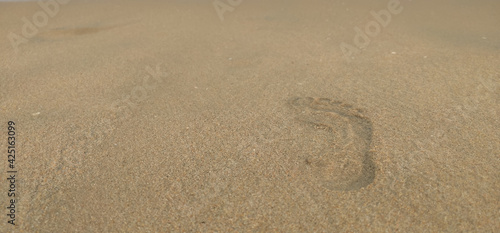 Footprints of a human in seashore sand with a selective focus on footprints . Copy space . Tipy view . Aerial