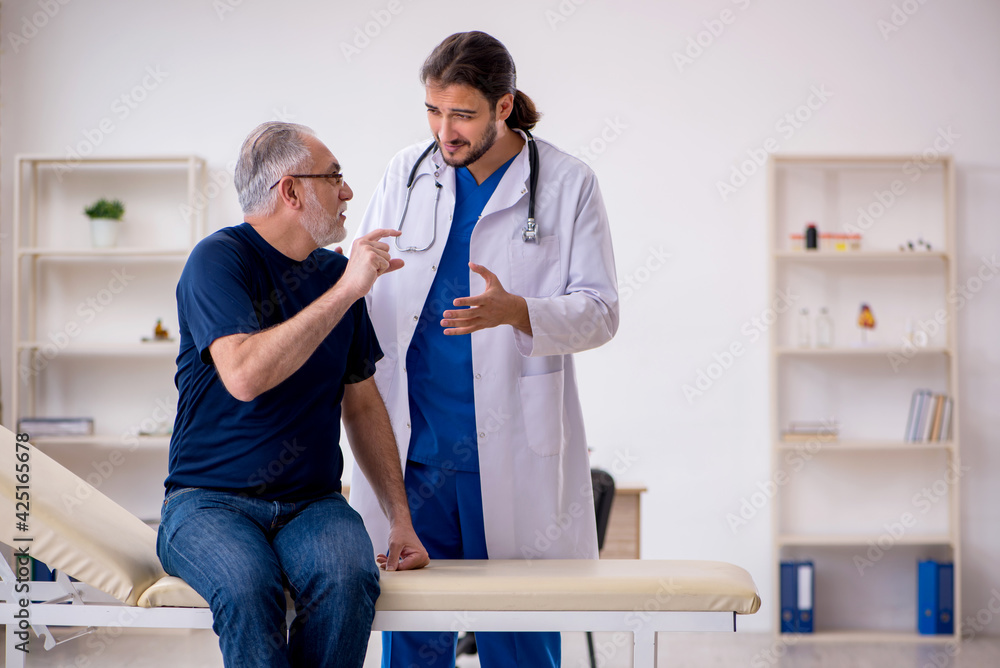 Fototapeta premium Old male patient visiting young male doctor