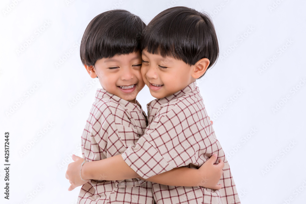 Twin boys hugging on white background. Portrait of little son hugging brother or friend. I missing you. Full length happy boy embracing glad brother or friend while standing indoor. Positive meeting Twin boys hugging on white background. Portrait of little son hugging brother or friend. I missing you. Full length happy boy embracing glad brother or friend while standing indoor. Positive meeting