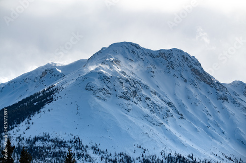 A beautiful winter view of northern Canada during March with wilderness, large snow capped mountain peaks surrounded by woods, forest and nature. 