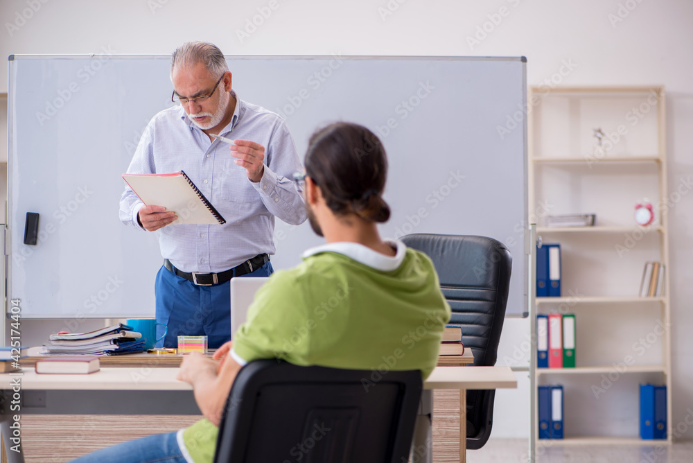 Obraz premium Old male teacher and young male student in the classroom