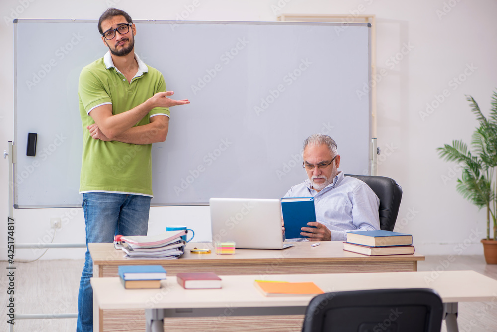 Old male teacher and young male student in the classroom