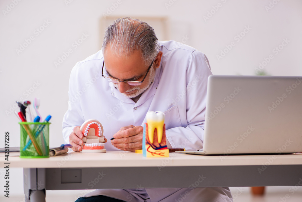 Old male dentist working in the clinic Old male dentist working in the clinic