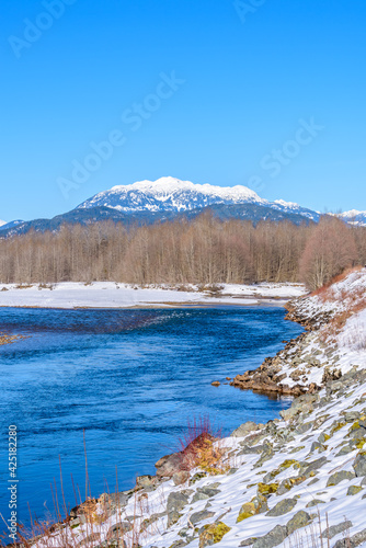 Majestic mountain river in winter over snow mountains and blue sky in Vancouver, Canada.