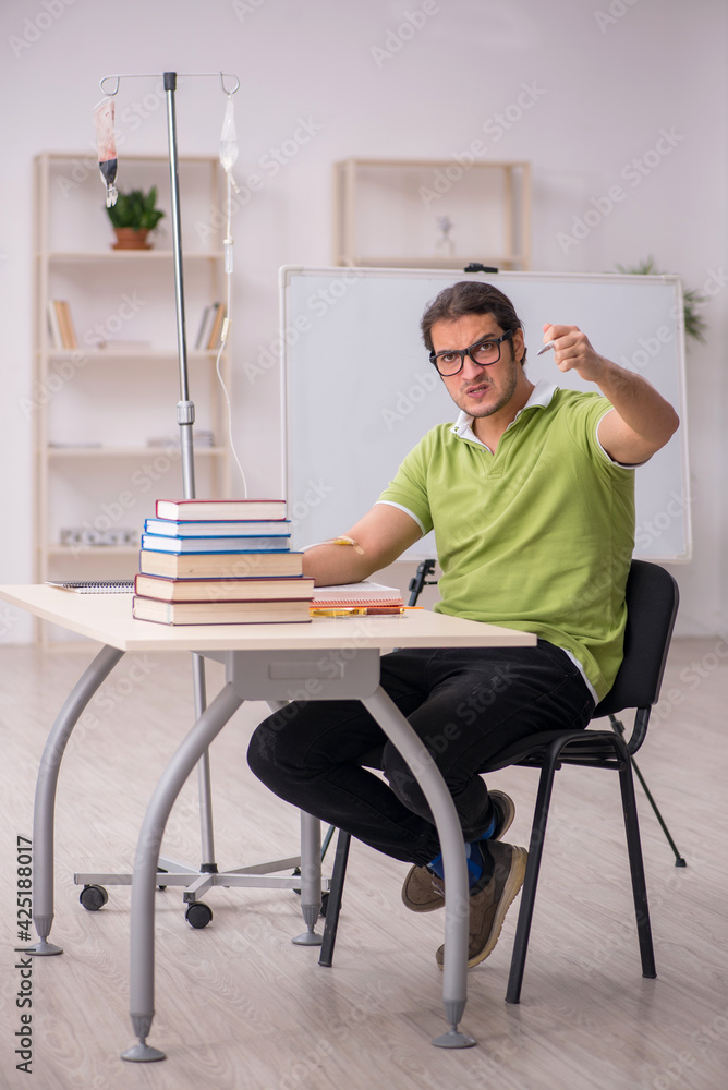Young sick male teacher student in blood transfusion concept Young sick male teacher student in blood transfusion concept