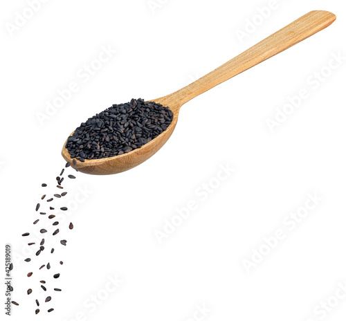black sesame seeds falling from wooden spoon