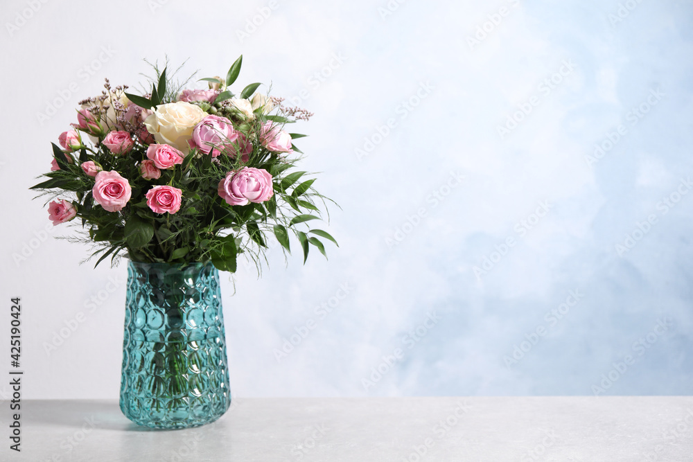 Beautiful bouquet with roses on light table. Space for text
