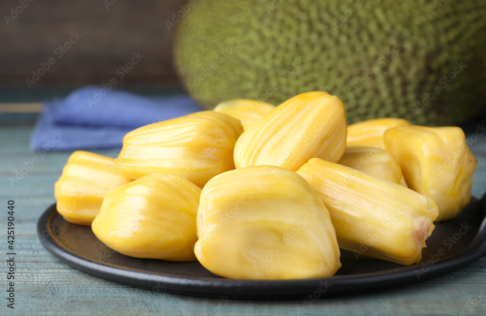 Fresh exotic jackfruit bulbs on light blue wooden table, closeup