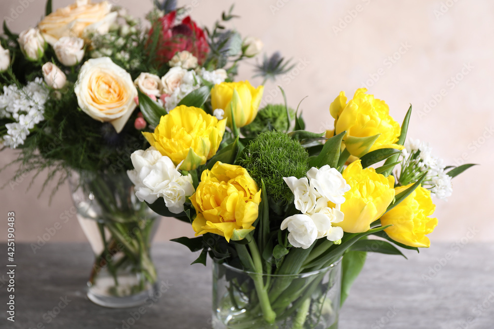Beautiful bouquets with fresh flowers on grey table, closeup