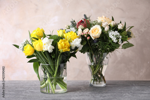Beautiful bouquets with fresh flowers on grey table