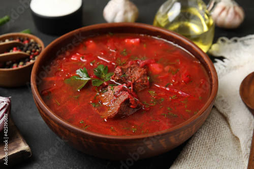 Stylish brown clay bowl with Ukrainian borsch served on black table photo