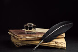 Feather pen, inkwell and old books on black table