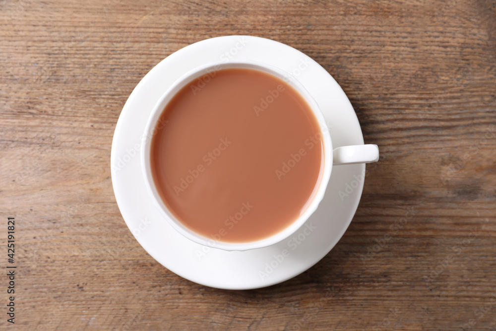 Delicious tea with milk in white cup on wooden table, top view Delicious tea with milk in white cup on wooden table, top view