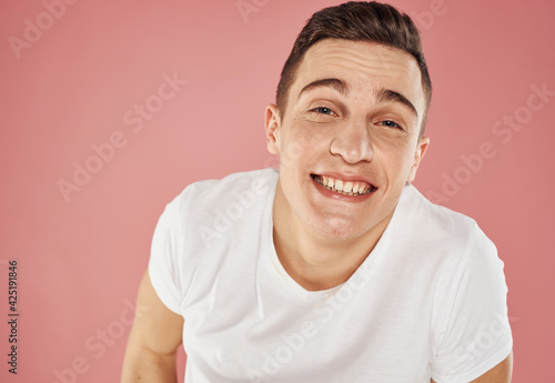 Happy man on pink background gesturing with hands in white t-shirt cropped view © SHOTPRIME STUDIO