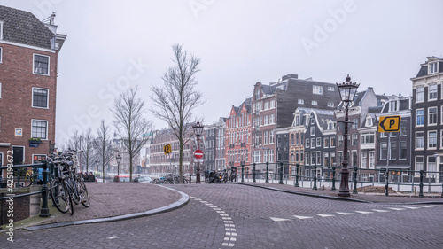  Amsterdam. Citizens have a rest on a bench. In the parapet there are bikes photo