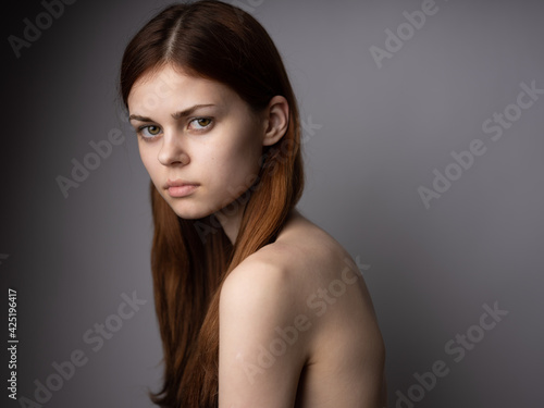 Red-haired woman naked shoulders side view dark background portrait close-up