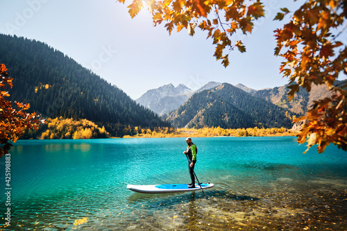 Man on stand up paddle board at mountain lake photo