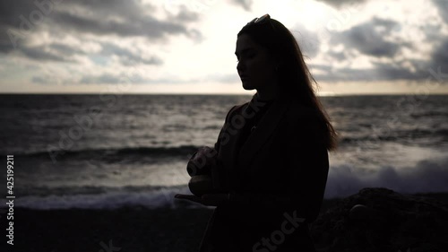 Woman playing on Tibetan singing bowl at Sunset on Beach. Close-up of woman hands playing on small Tibetan Singing Bowl. Concept of sound vibration therapy, meditation zen practice with calm sounds. photo