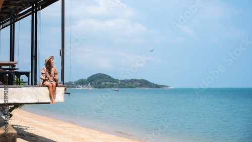 Portrait image of a beautiful young asian woman sitting and relaxing by the sea