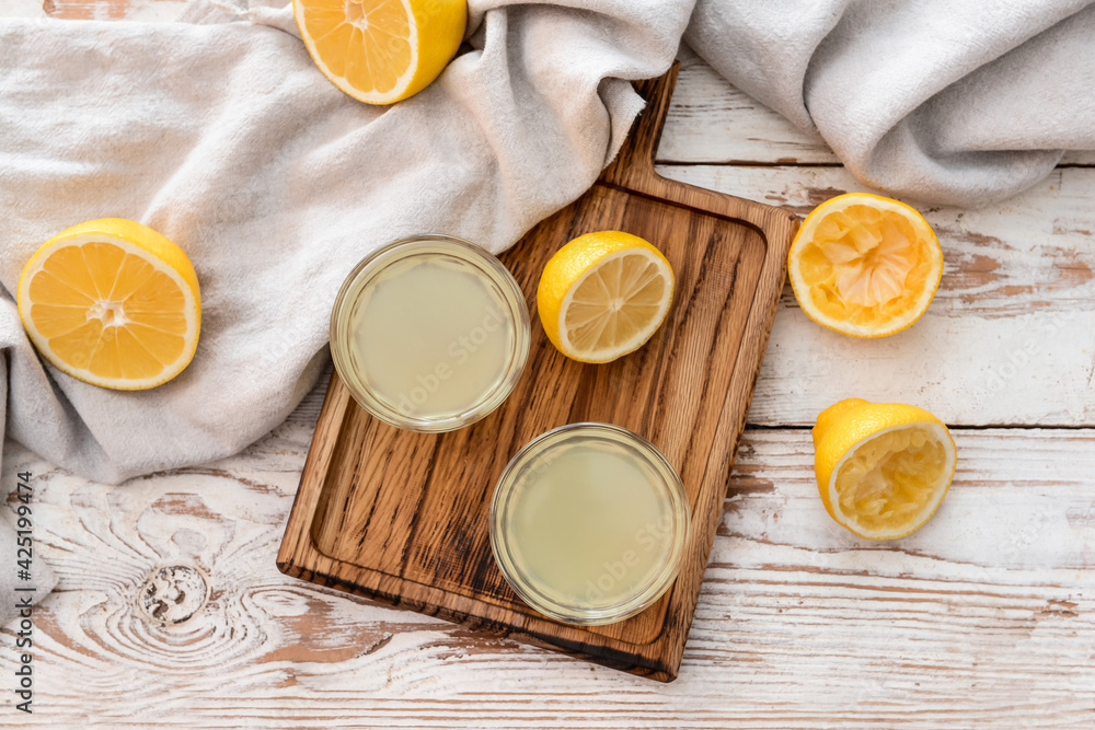 Fresh lemons and glasses of juice on light wooden background Fresh lemons and glasses of juice on light wooden background