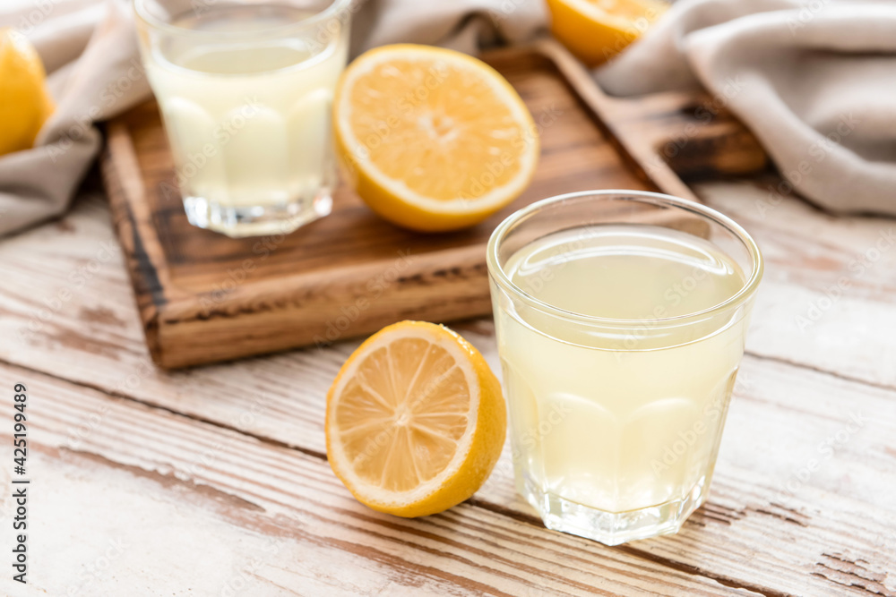 Fresh lemons and glasses of juice on light wooden background Fresh lemons and glasses of juice on light wooden background