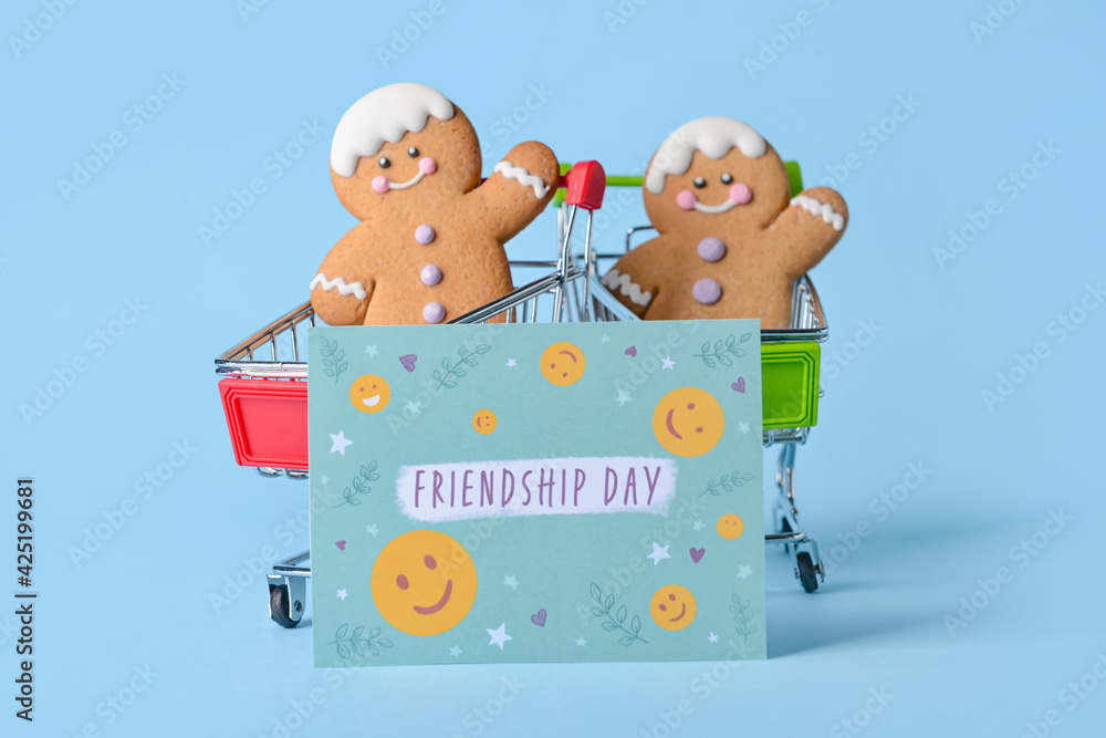 Shopping carts with cookies and greeting card for Friendship Day on color background Shopping carts with cookies and greeting card for Friendship Day on color background