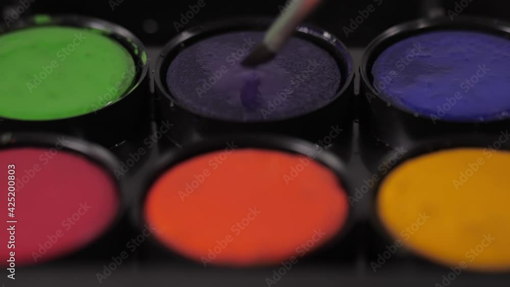 artist painter mixing water and purple watercolor with brush artist painter mixing water and purple watercolor with brush