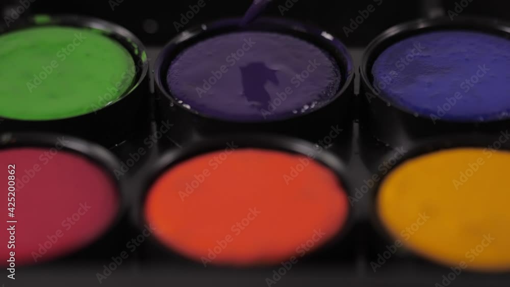 artist painter mixing water and purple watercolor with brush artist painter mixing water and purple watercolor with brush