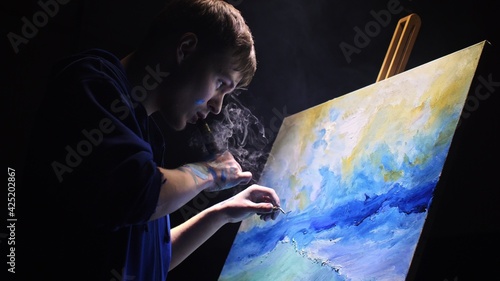 Artist copyist paint seascape with ship in ocean. Vaper smoke vape e-cigarette. Craftsman decorator draw as boat sail on blue sea with acrylic color. photo