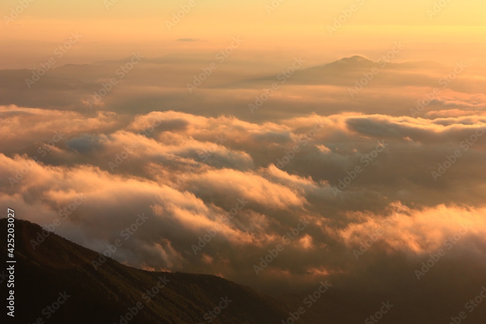 八ヶ岳の風景。朝日にオレンジ色に染まる雲海。