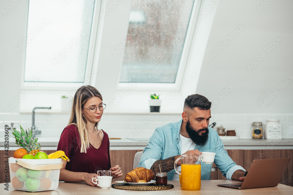 Couple using laptop during breakfast at home