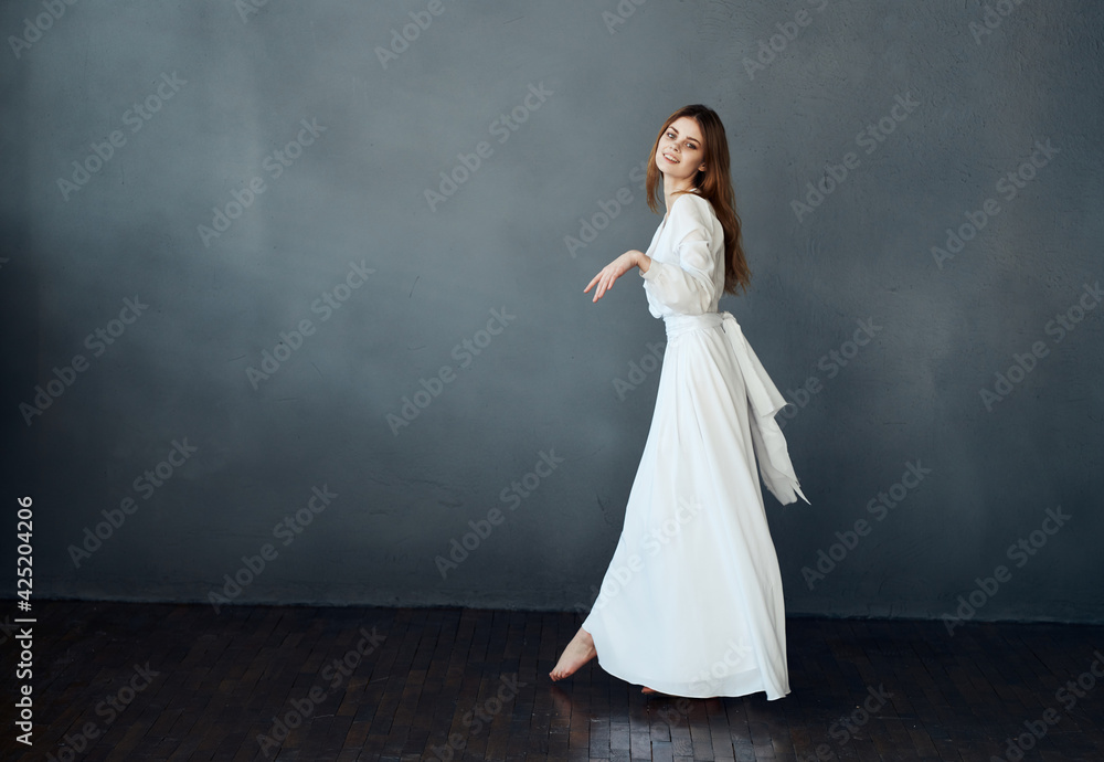 Charming lady in a white dress on a gray background dance gesticulating with her hands Copy Space model