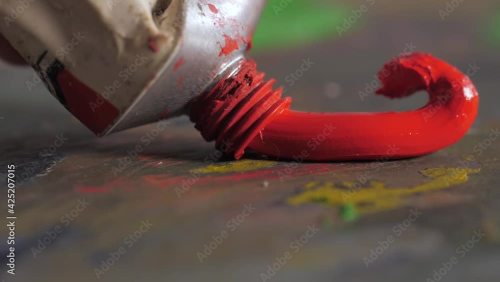 artist painter squeezing red oil paint tube on to a palette Stock ビデオ
