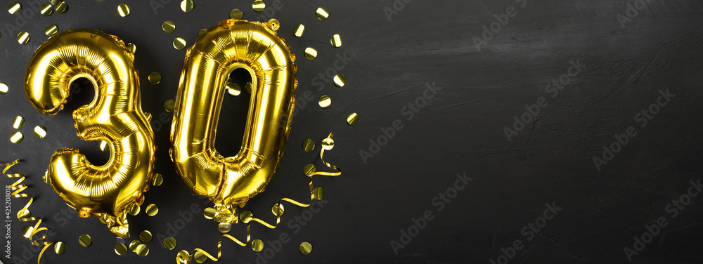 gold foil balloon number thirty. Birthday or anniversary greeting card with the inscription 30. Black concrete background. Anniversary celebration. Banner. gold foil balloon number thirty. Birthday or anniversary greeting card with the inscription 30. Black concrete background. Anniversary celebration. Banner.