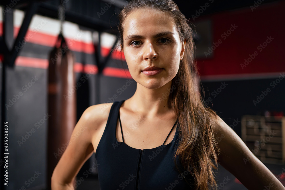 Portrait of beautiful athletic woman with perfect muscular body looks at camera in the gym centre. Healthy lifestyle, bodybuilding. Working out in fitness. Body training and exercise concept