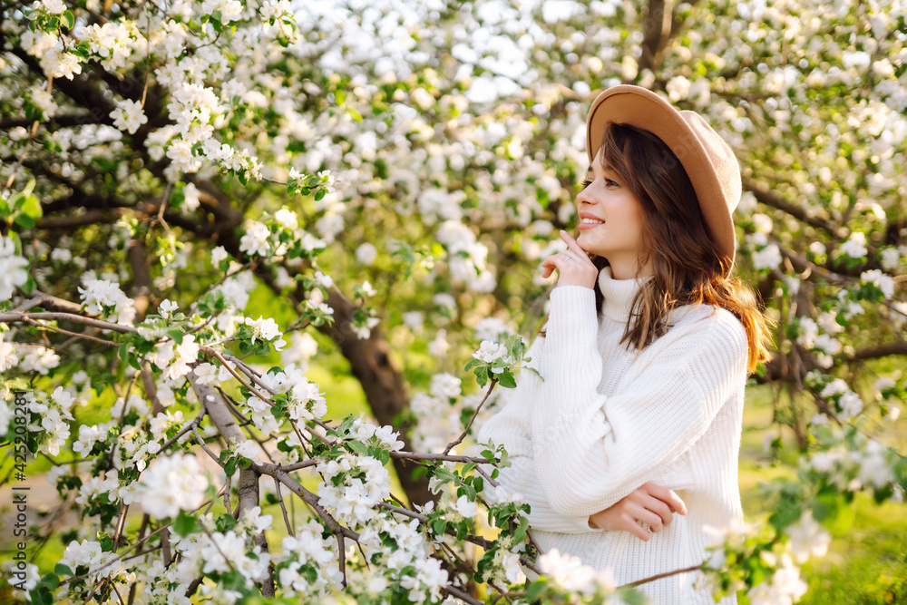 Smiling woman with the hat posing in blooming spring park. The concept of relax, travel, freedom and spring vacation. Fashion style. Smiling woman with the hat posing in blooming spring park. The concept of relax, travel, freedom and spring vacation. Fashion style.