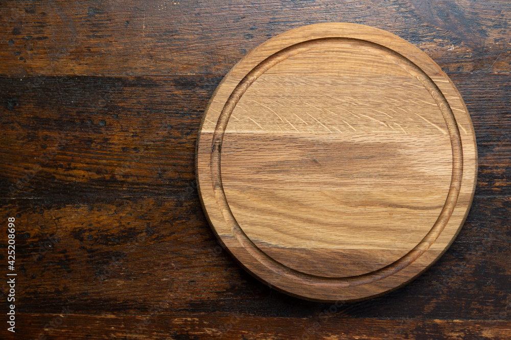 Empty round cutting board on a wooden table. Space for text. Empty round cutting board on a wooden table. Space for text.