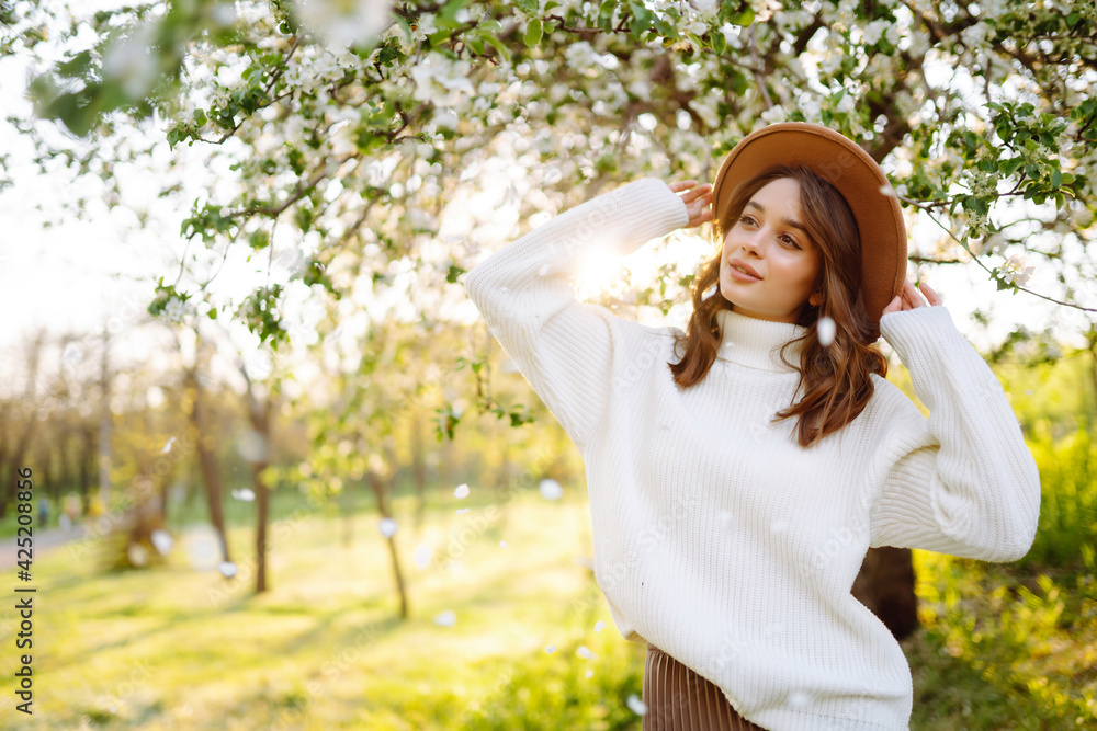 Smiling woman with the hat posing in blooming spring park. The concept of relax, travel, freedom and spring vacation. Fashion style. Smiling woman with the hat posing in blooming spring park. The concept of relax, travel, freedom and spring vacation. Fashion style.