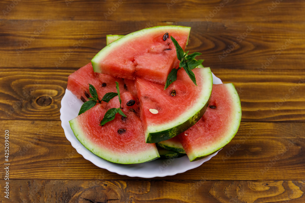 Fresh ripe sliced watermelon in white plate on a wooden table Fresh ripe sliced watermelon in white plate on a wooden table