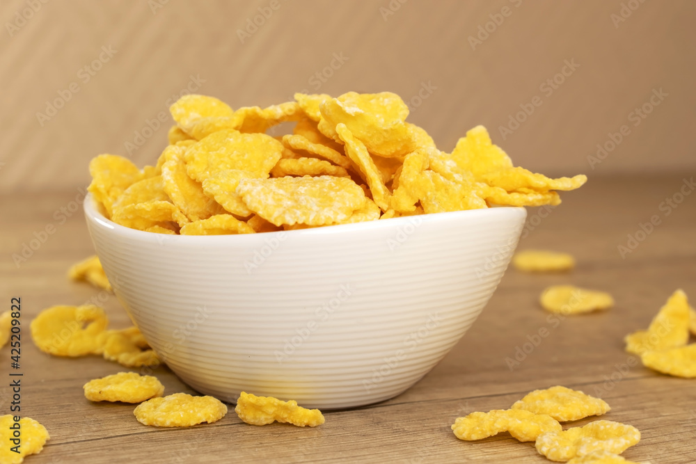 Healthy breakfast. Yellow cornflakes in a white plate on a wooden table. Healthy breakfast. Yellow cornflakes in a white plate on a wooden table.