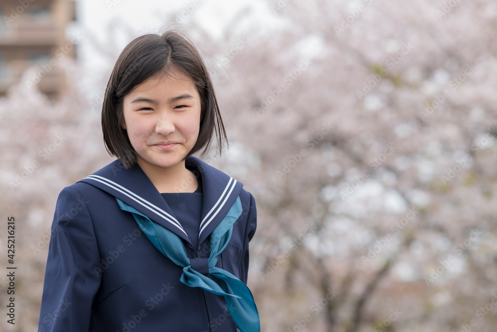 桜の咲く河川敷をあるく新中学生