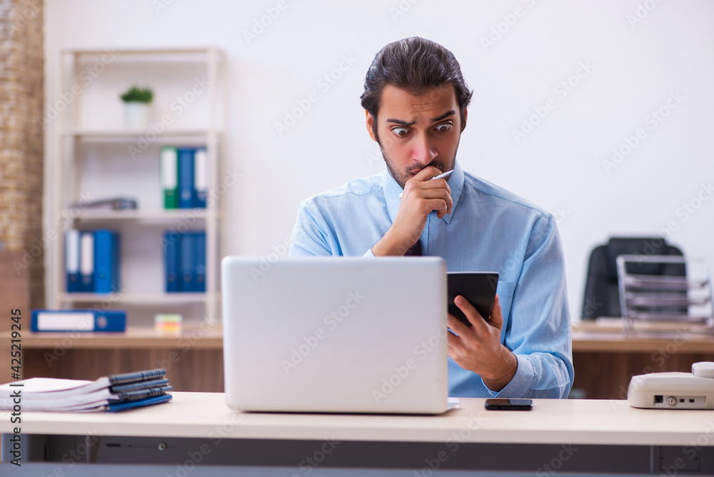 Young male bookkeeper working in the office Young male bookkeeper working in the office