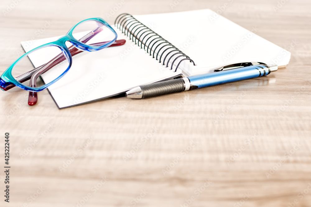 Notebook, pen and reading glasses on wooden table. Notebook, pen and reading glasses on wooden table.