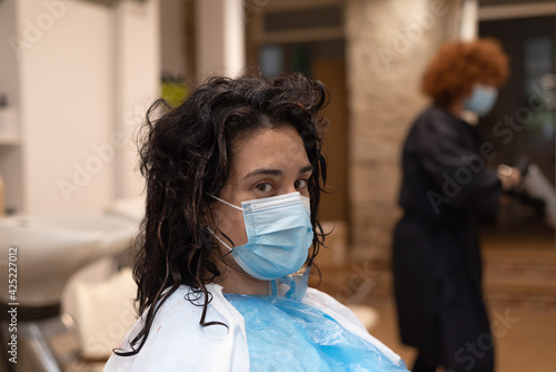 Young woman with mask at hair salon looking to camera