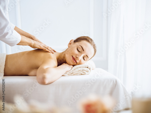 Beautiful woman enjoying back massage with closed eyes. Spa treatment concept.
