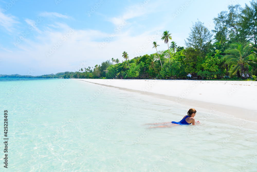 Woman swimming in caribbean sea turquoise transparent water. Tropical beach in the Kei Islands Moluccas, summer tourist destination in Indonesia.