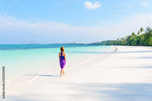 Woman walking on tropical beach. Rear view white sand beach turquoise trasparent water caribbean sea real people. Indonesia Kei Islands Moluccas travel destination. © fabio lamanna