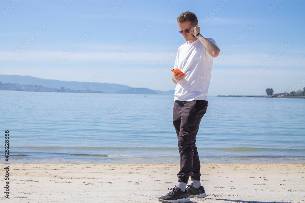 young man on the beach using mobile phone young man on the beach using mobile phone