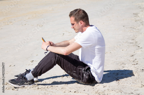 young man on the beach using mobile phone